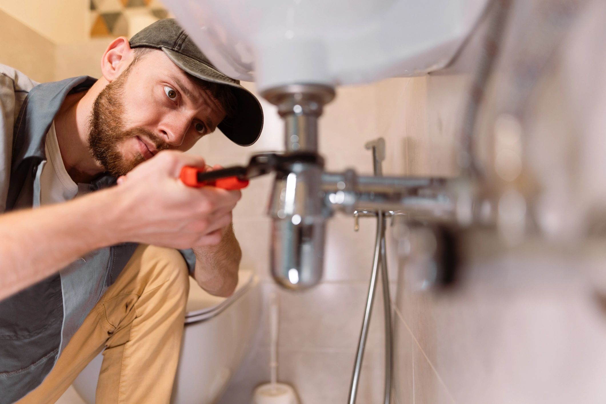 Plumber repairing a sink leak with a wrench